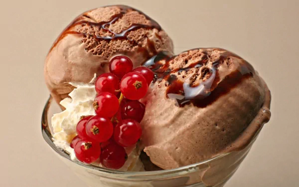 A delicious bowl of chocolate ice cream topped with whipped cream and fresh currants, set against a soft background, creating an enticing food-themed HD desktop wallpaper.