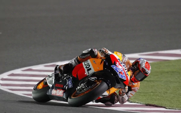 High-definition wallpaper of a Honda MotoGP rider expertly leaning into a curve on a racetrack.