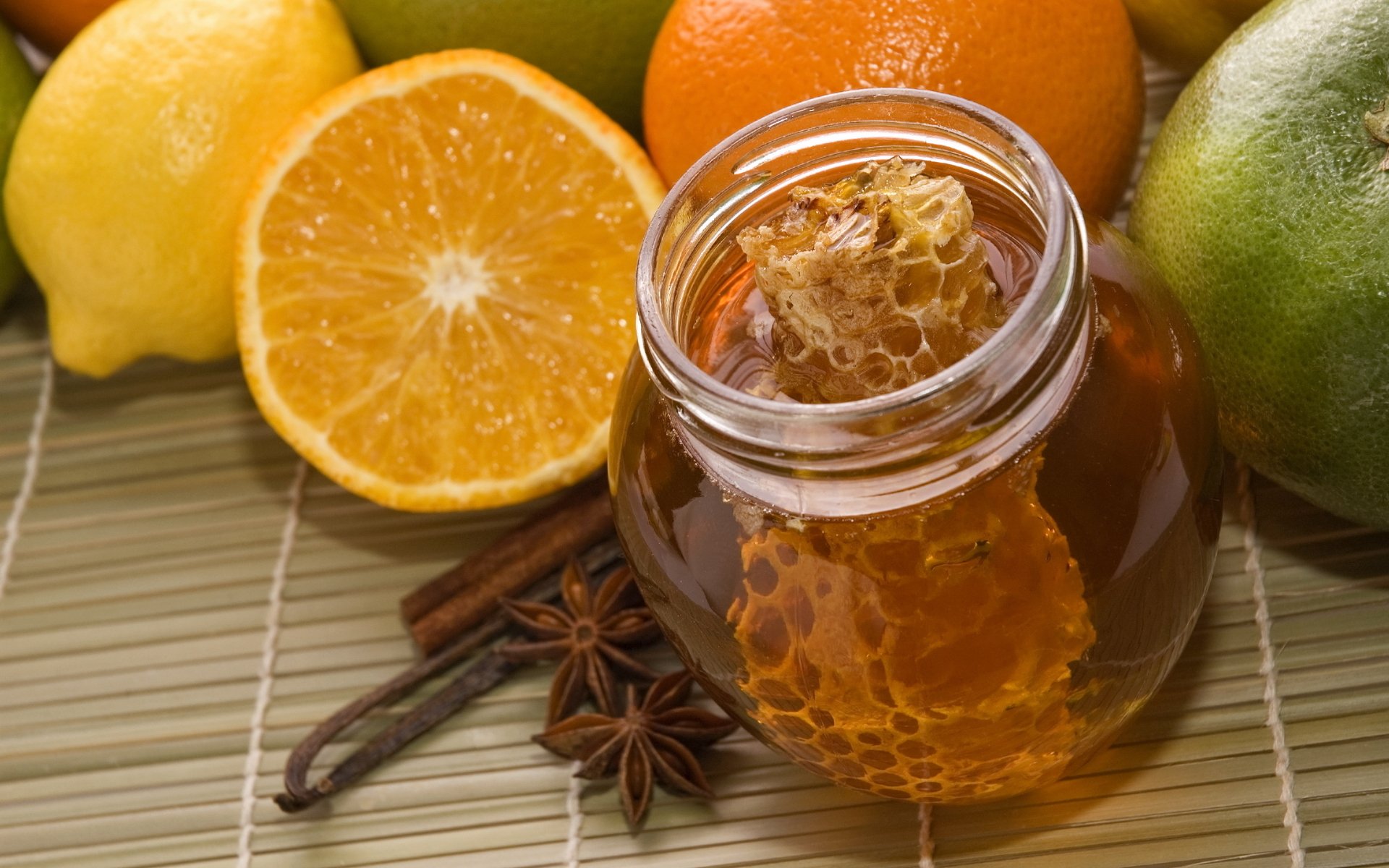 HD desktop wallpaper showing a jar of honey with honeycomb surrounded by citrus fruits and star anise, highlighting a vibrant food and honey theme.