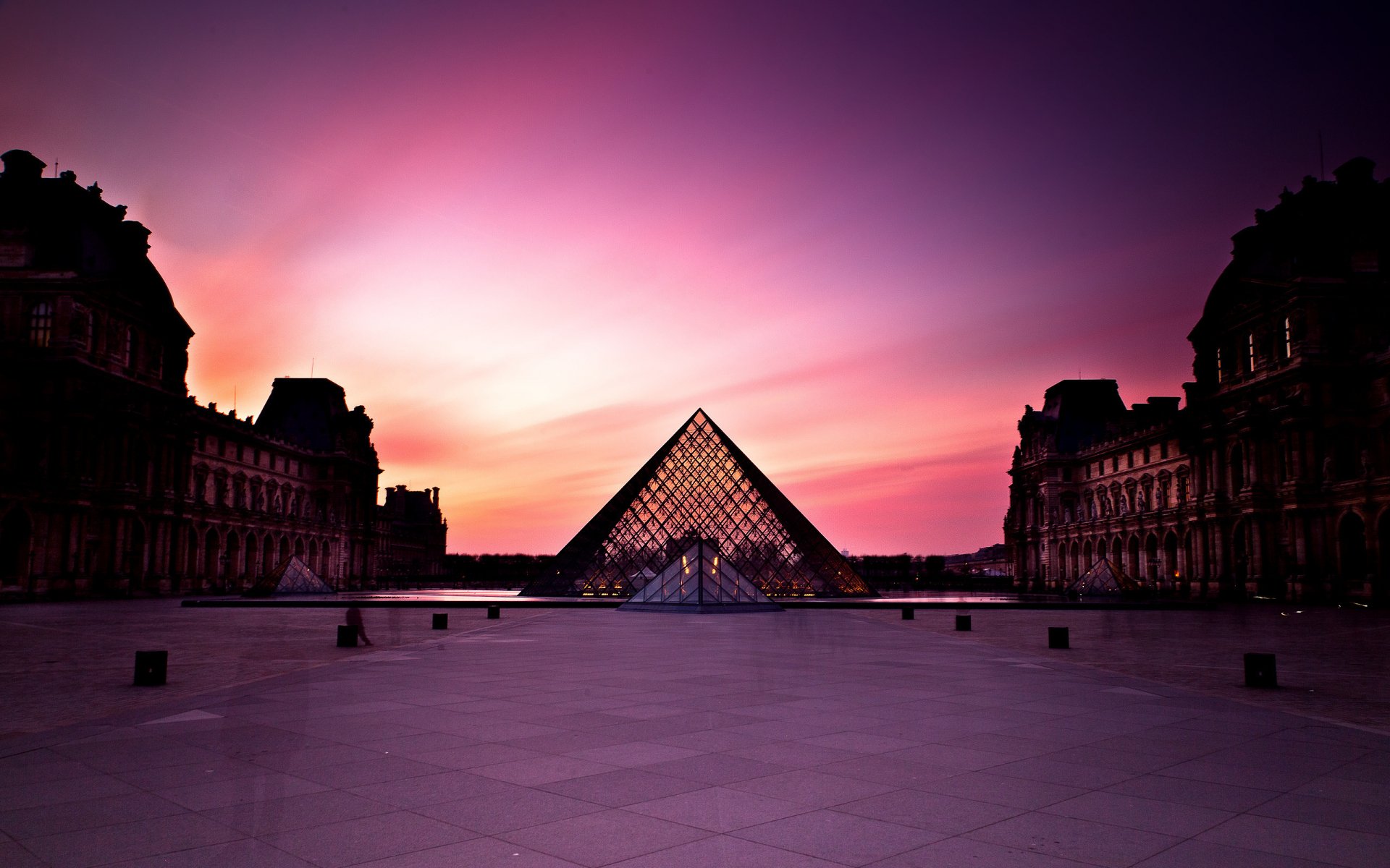 HD desktop wallpaper featuring the Louvre Pyramid at sunset in Paris, showcasing the iconic man-made glass structure against a vibrant sky.