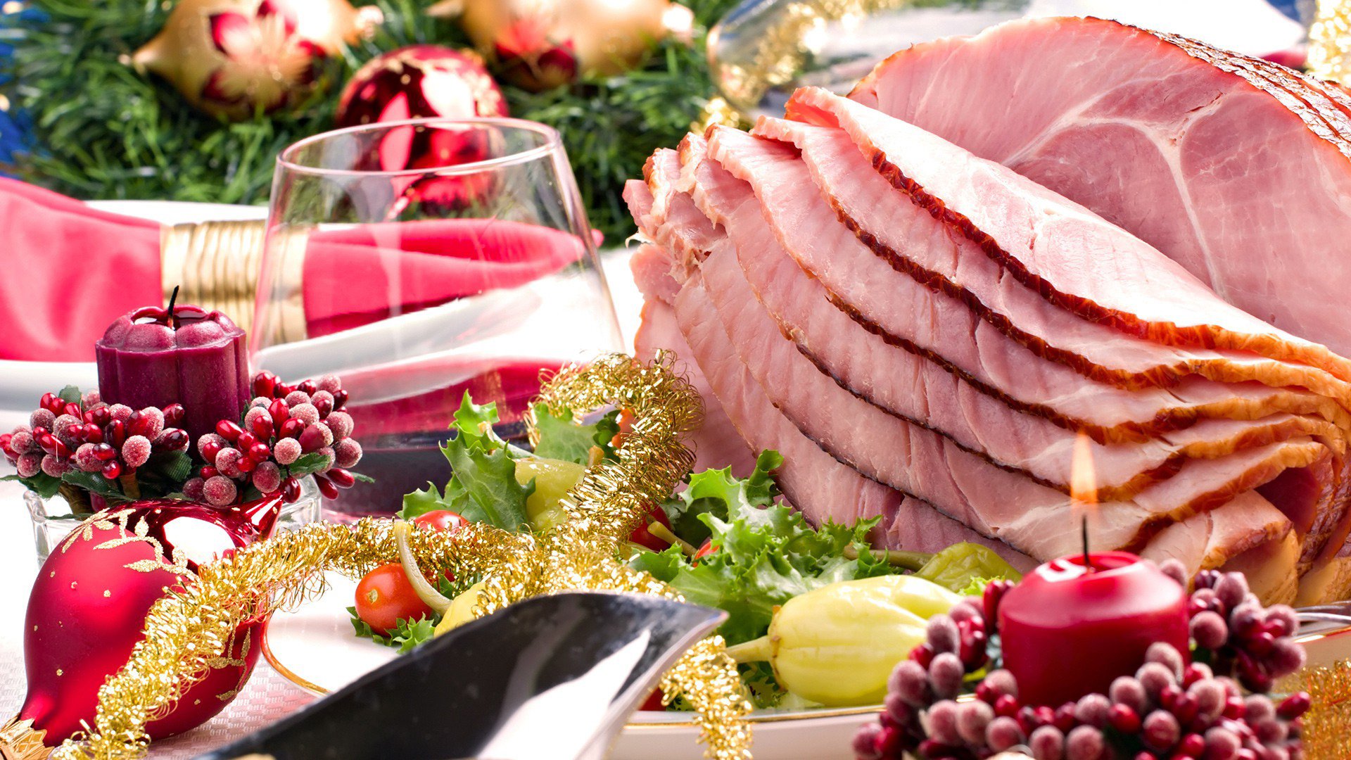 HD PC desktop wallpaper featuring a festive still life with sliced ham, holiday decorations, candles, and a glass of red wine, highlighting a rich food display.