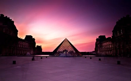 HD desktop wallpaper featuring the Louvre Pyramid at sunset in Paris, showcasing the iconic man-made glass structure against a vibrant sky.
