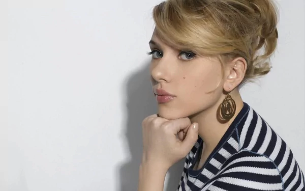 HD desktop wallpaper featuring a blonde woman, tagged as Scarlett Johansson, in a striped shirt, posing against a plain background, with her chin resting on her hand and gazing to the side.