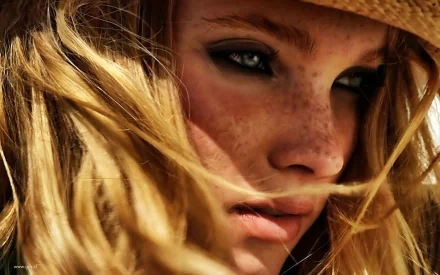 Close-up HD desktop wallpaper of a woman with freckles and blonde hair partially covered by a hat, featuring Elsa Hosk.