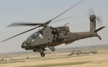 HD desktop wallpaper featuring a Boeing AH-64 Apache attack helicopter in flight over a desert landscape, showcasing military aviation technology.