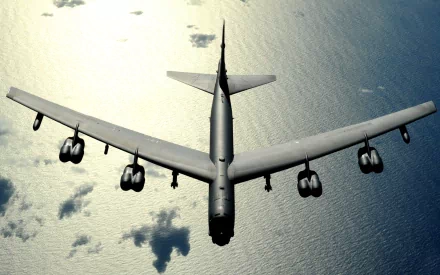 HD desktop wallpaper showing a top-down view of a Boeing B-52 Stratofortress military bomber flying over the ocean.