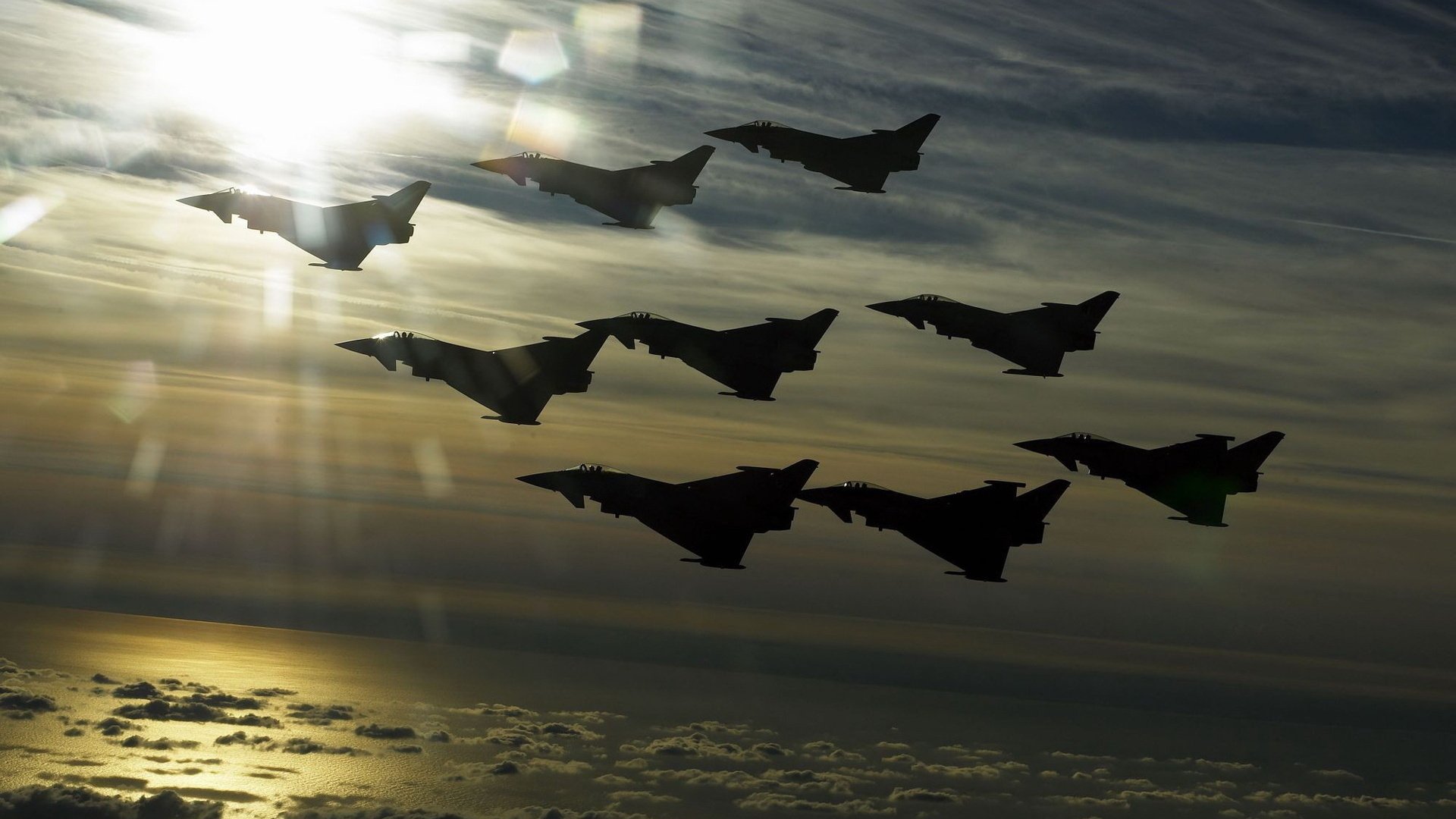 HD PC desktop wallpaper and background: silhouetted military jets in formation at sunset during an air show over cloud tops.