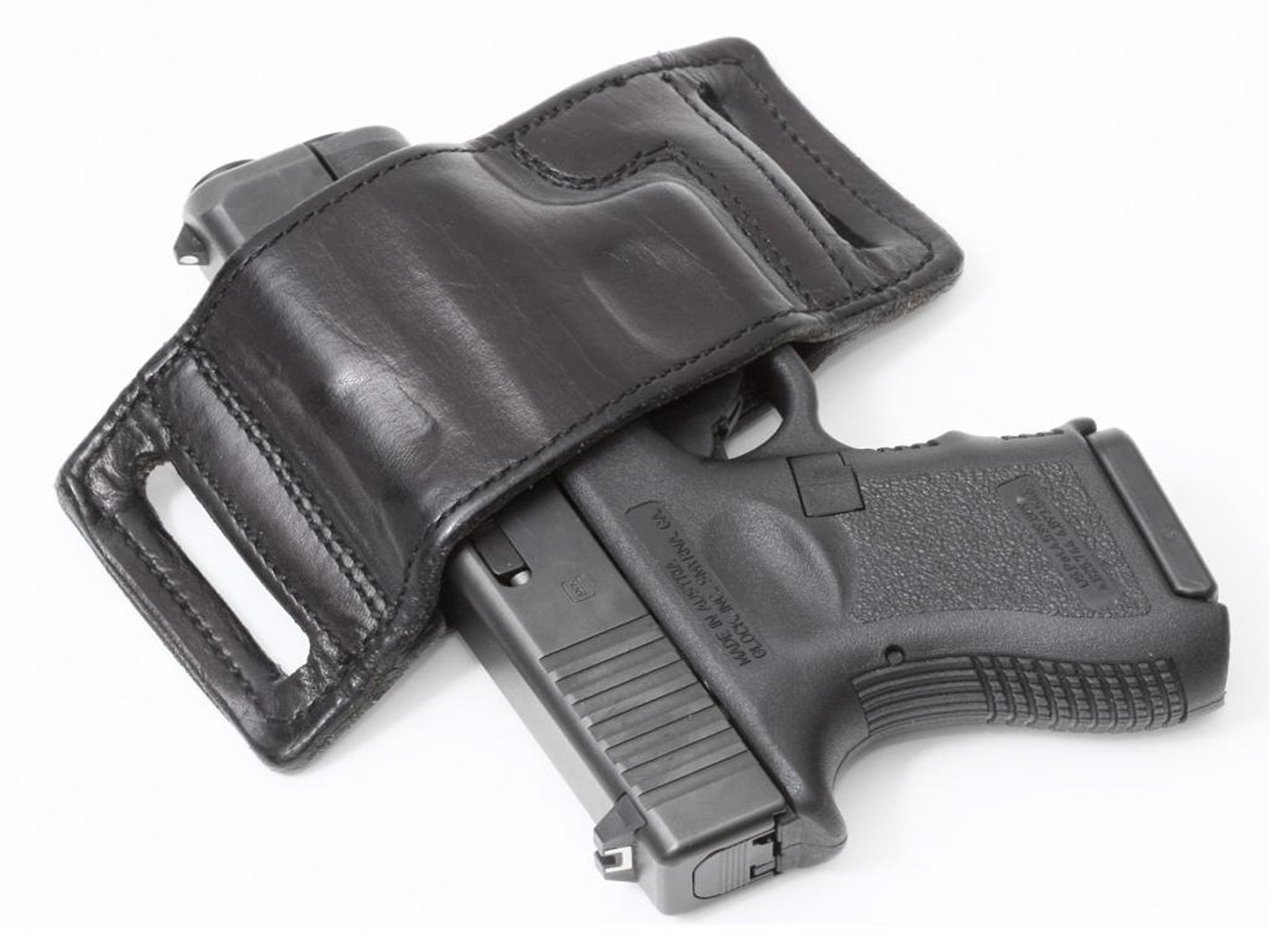 HD desktop wallpaper featuring a Glock pistol partly concealed in a black leather holster, with a white background highlighting the man-made firearm.