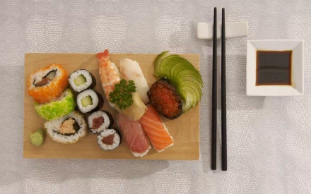 HD PC desktop wallpaper featuring an assortment of sushi, including rolls, nigiri, avocado slices, soy sauce, and chopsticks on a textured surface.