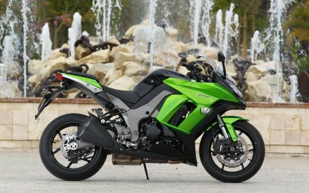 A sleek Kawasaki motorcycle in vibrant green, positioned elegantly near a fountain, captures the essence of high-performance vehicles in this HD desktop wallpaper.