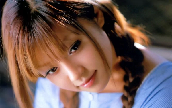 HD desktop wallpaper featuring an Asian woman with long, braided hair, wearing a blue top, and softly smiling, creating a serene and captivating background.