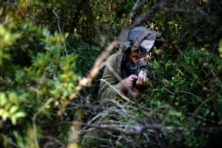 HD PC desktop wallpaper/background: military soldier in camouflage and ghillie hood aiming a rifle while concealed in dense green foliage.