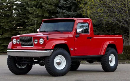 A vibrant red Jeep with rugged tires, parked against a backdrop of lush trees, showcased as an HD desktop wallpaper and background.