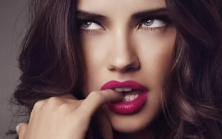 HD PC desktop wallpaper featuring a close-up portrait of celebrity Adriana Lima with bold makeup and expressive eyes.