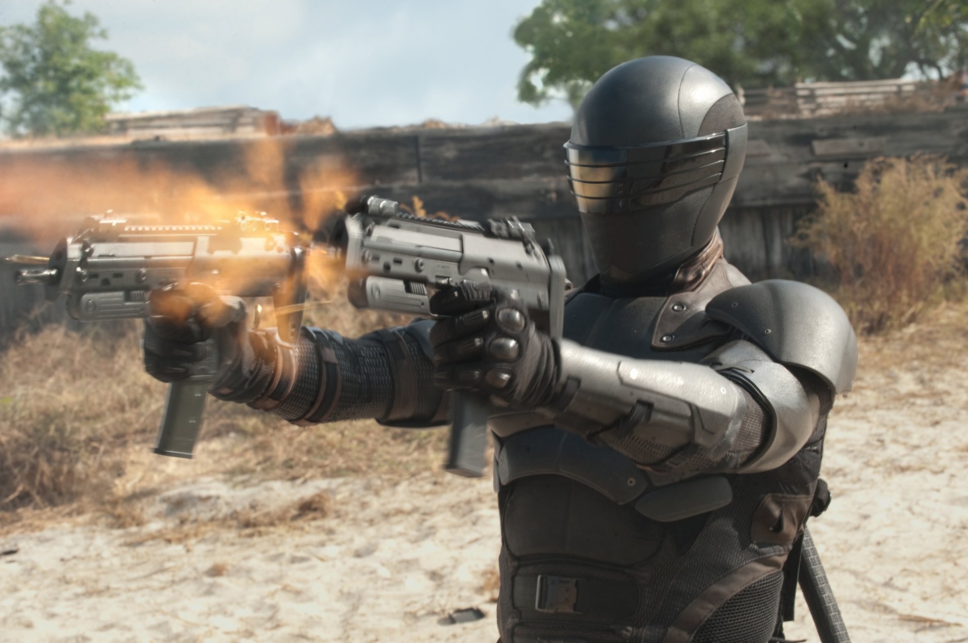 HD PC desktop wallpaper from the movie G.I. Joe: Retaliation — armored, helmeted soldier firing twin pistols amid a dusty battlefield.