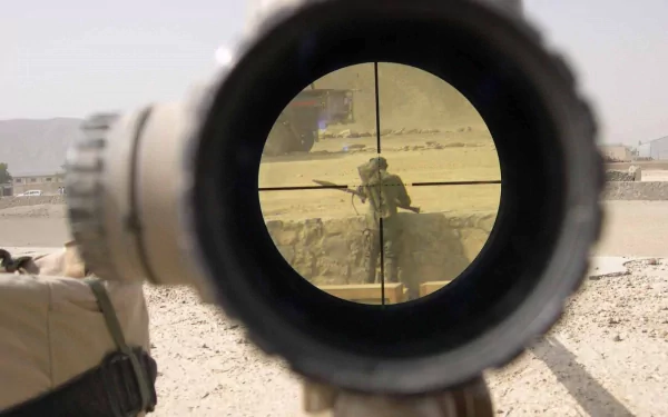 HD PC desktop wallpaper showing a military sniper aiming through a rifle scope at a soldier in a desert environment.