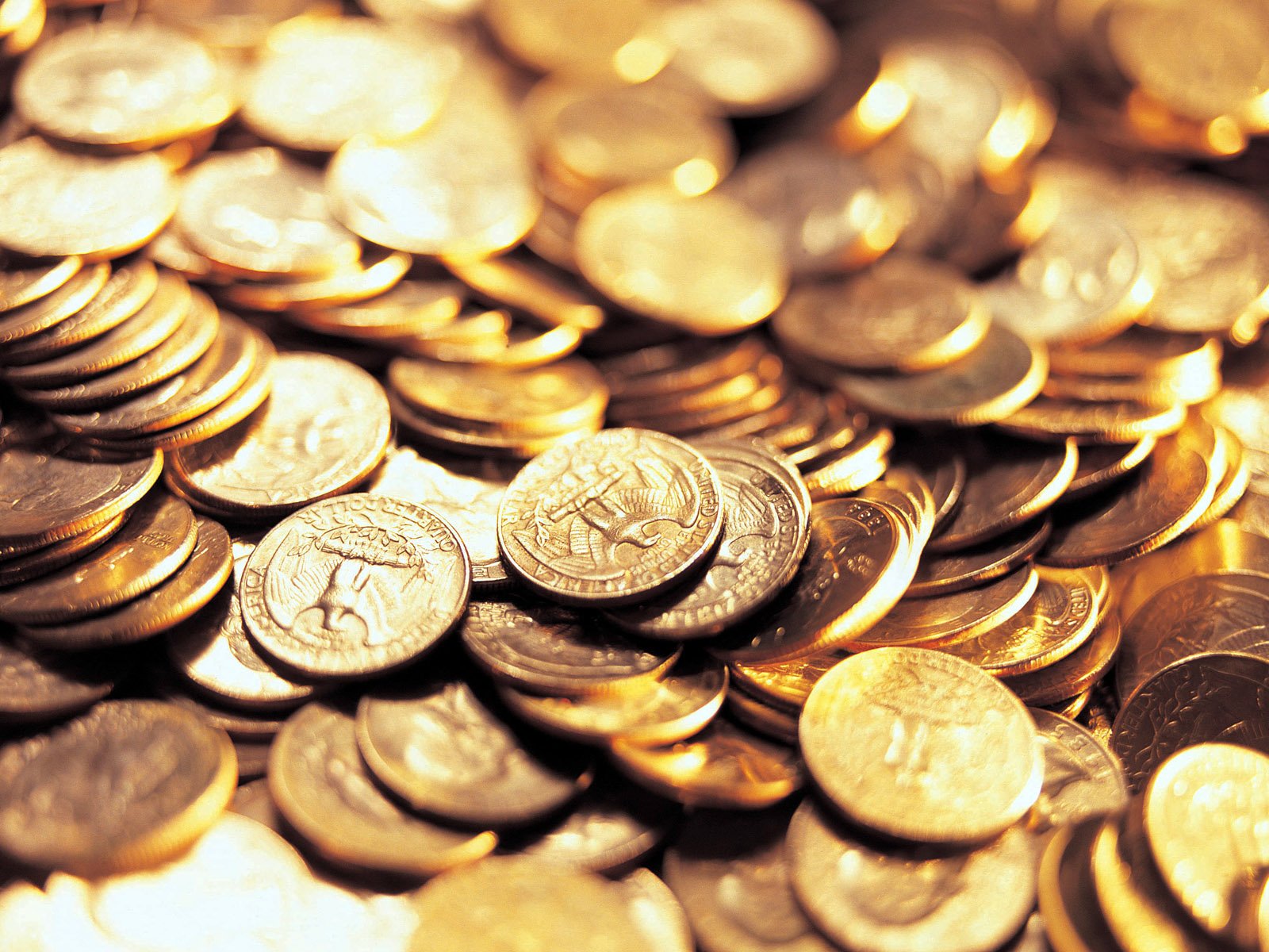 HD desktop wallpaper featuring a close-up of numerous man-made coins scattered and stacked, highlighting their varied designs and metallic shine.