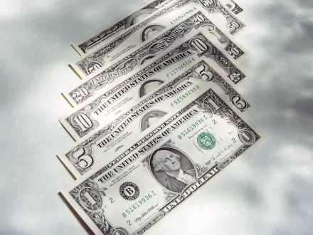 HD desktop wallpaper featuring an arranged fan of U.S. dollar bills on a light surface, highlighting man-made currency details.