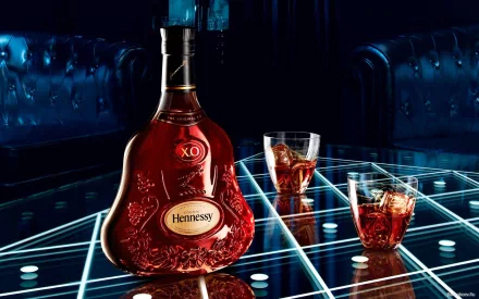 A striking HD wallpaper featuring a bottle of Hennessy XO and two glasses filled with whisky, set against a stylish, modern backdrop with a glowing geometric pattern.