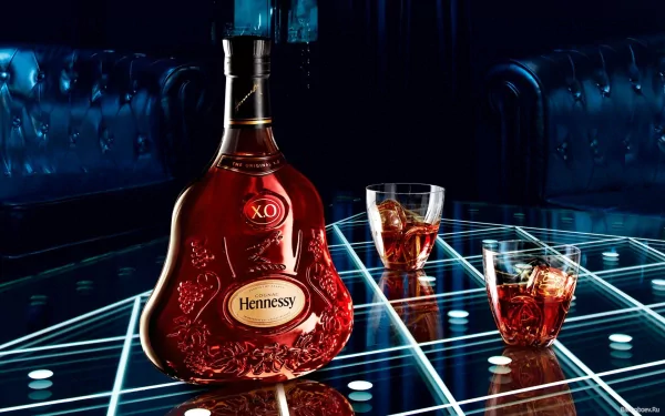 A striking HD wallpaper featuring a bottle of Hennessy XO and two glasses filled with whisky, set against a stylish, modern backdrop with a glowing geometric pattern.