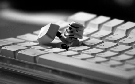 HD desktop wallpaper featuring a LEGO Stormtrooper from Star Wars holding a large keyboard key, set against a monochrome keyboard background.