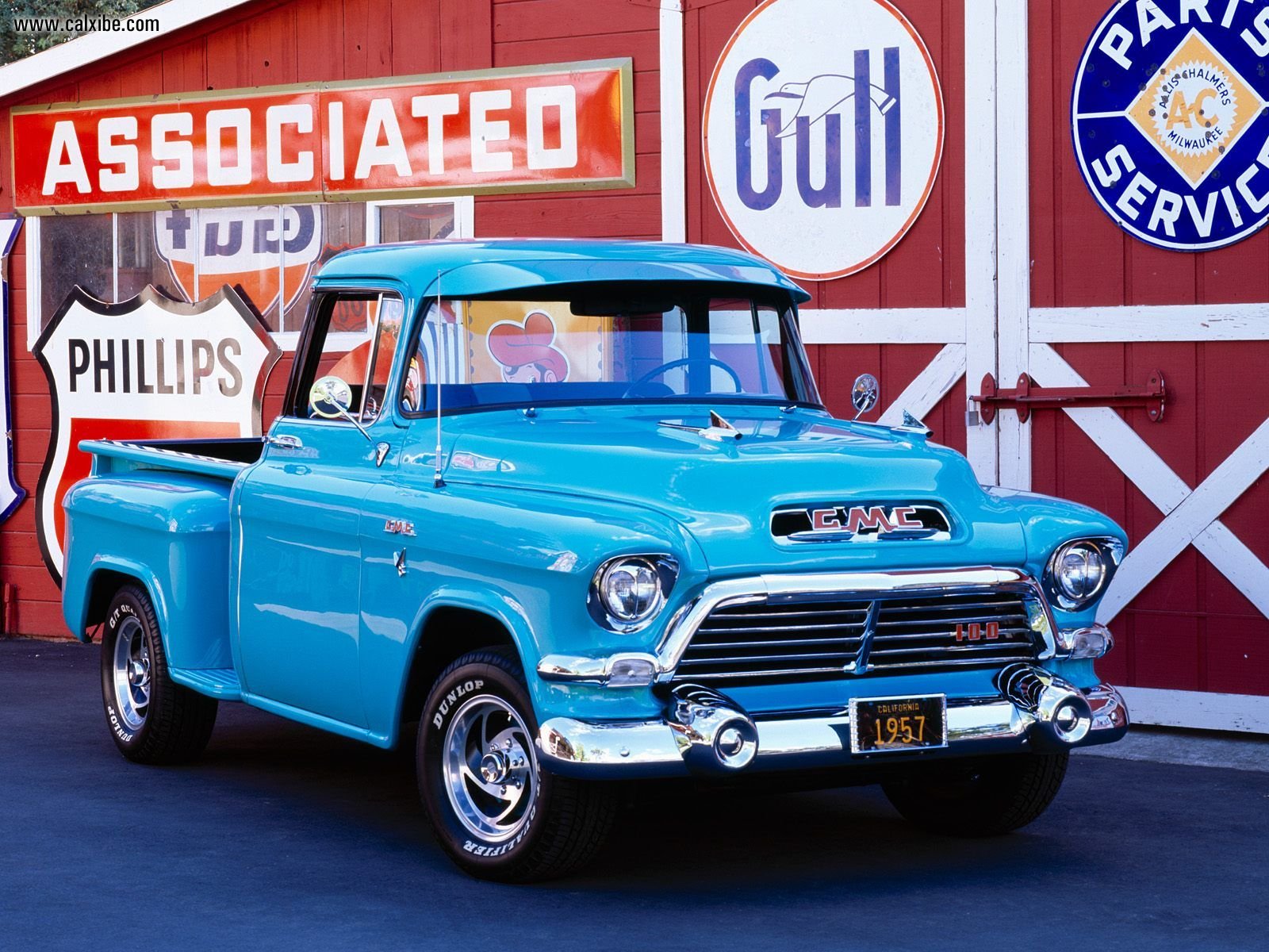 HD PC desktop wallpaper background of a classic turquoise GMC vehicle, a vintage pickup parked in front of retro service and gas station signs.