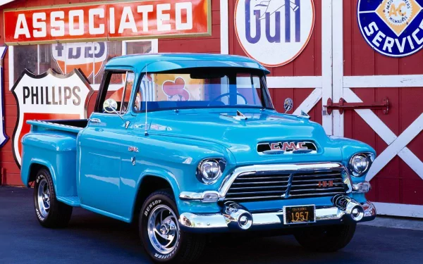 HD PC desktop wallpaper background of a classic turquoise GMC vehicle, a vintage pickup parked in front of retro service and gas station signs.