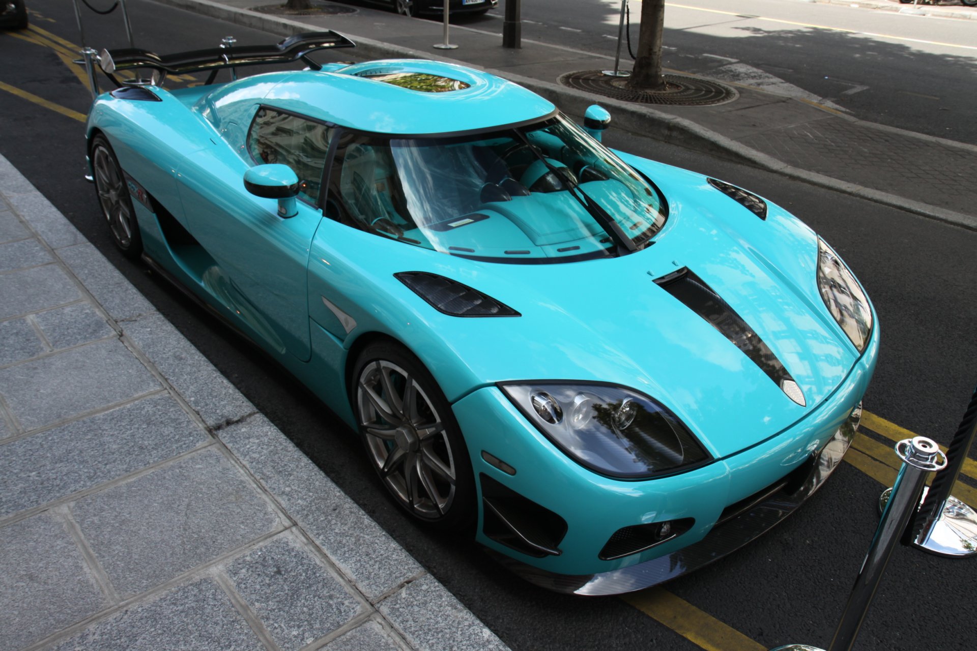 Turquoise Koenigsegg vehicle on a city street, captured in high detail — HD PC desktop wallpaper and background showing glossy aerodynamic body and reflective surfaces from a slight high angle.