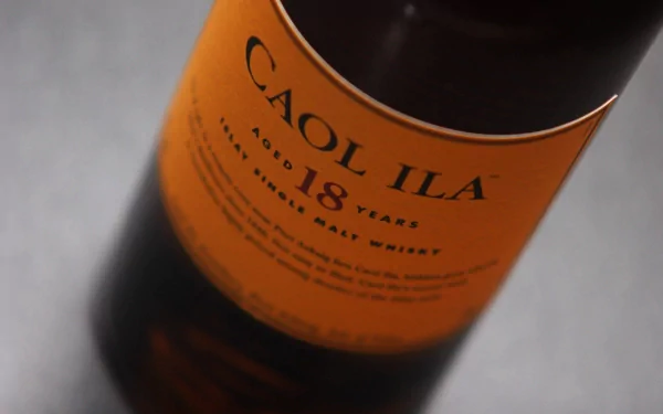 A close-up of a Caol Ila 18 Years old Scotch whisky bottle, showcasing its distinct orange label, set against a neutral background for a sophisticated HD desktop wallpaper.