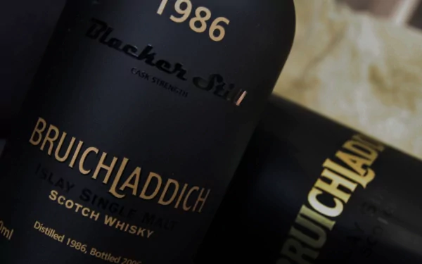 A close-up of Bruichladdich 1986 Scotch whisky bottles, highlighting their elegant black labels and gold lettering, set against a blurred background. 4K Ultra HD wallpaper.
