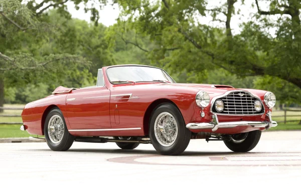 HD PC desktop wallpaper and background: red Aston Martin DB2 convertible vehicle parked before leafy trees, photographed in bright daylight.