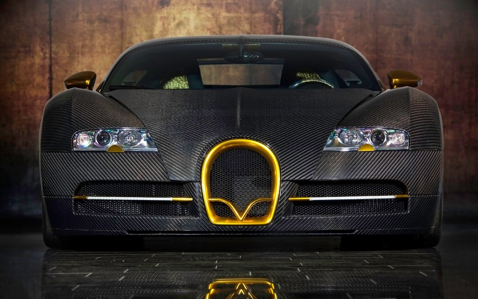 HD PC desktop wallpaper background showing a front view of a black carbon-fiber Bugatti with gold trim, dramatic lighting and floor reflection.