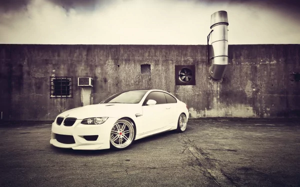 White BMW vehicle coupe parked against a weathered concrete wall with industrial vents, stylized vignette — 4K Ultra HD PC desktop wallpaper and background.