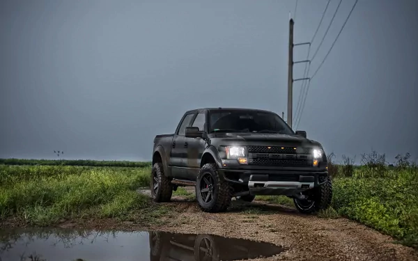 A Ford Raptor truck parked on a dirt path near a puddle, featured in a 4K Ultra HD PC desktop wallpaper showcasing the rugged vehicle.