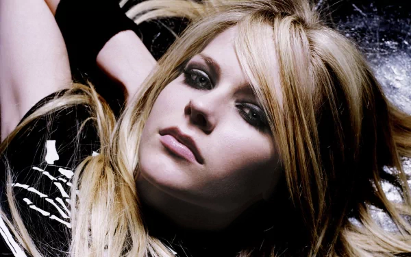 HD desktop wallpaper featuring Avril Lavigne with a close-up shot of her lying down, showcasing her iconic punk rock style with dark eye makeup and blonde hair. Tags: music, Avril Lavigne.