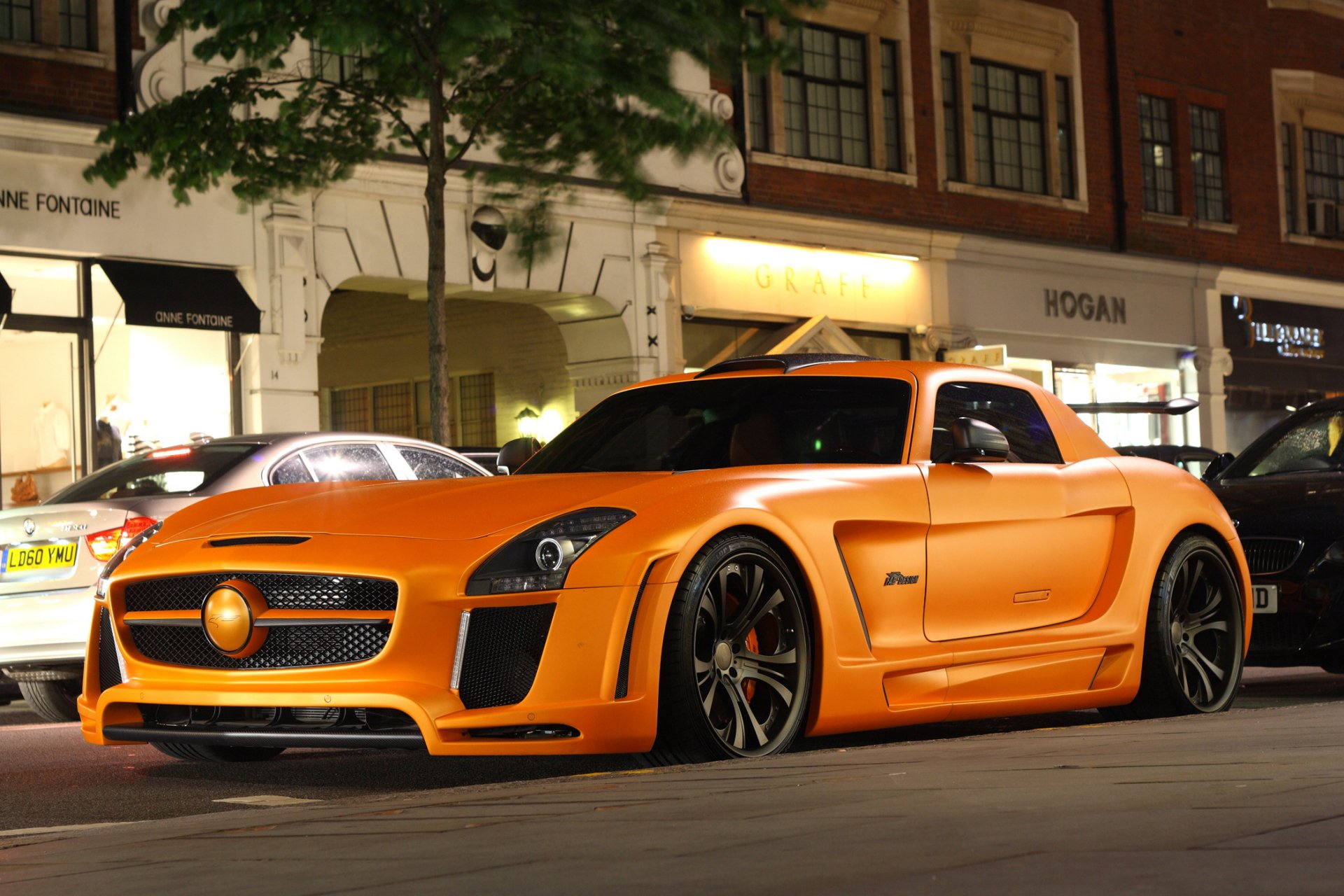 A striking orange Mercedes vehicle parked on an urban street, set against a softly lit backdrop, making for an impressive HD PC desktop wallpaper and background.