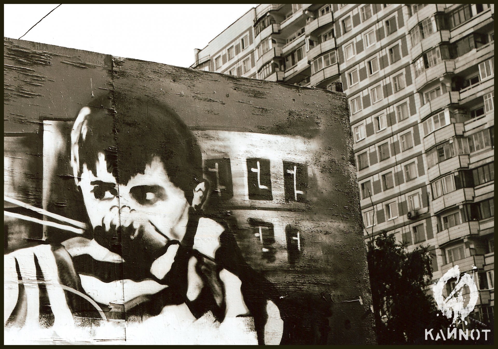 A striking artistic graffiti piece features a boy with an intense expression, set against a backdrop of modern architecture, creating a captivating HD wallpaper for any background.