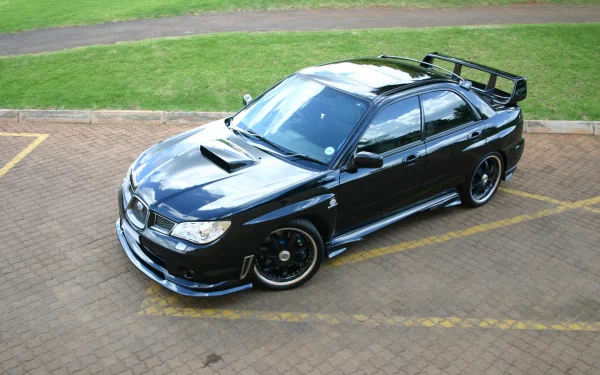 HD PC desktop wallpaper: overhead view of a glossy black Subaru performance sedan with roof scoop and rear wing parked on a paved lot next to a grassy path
