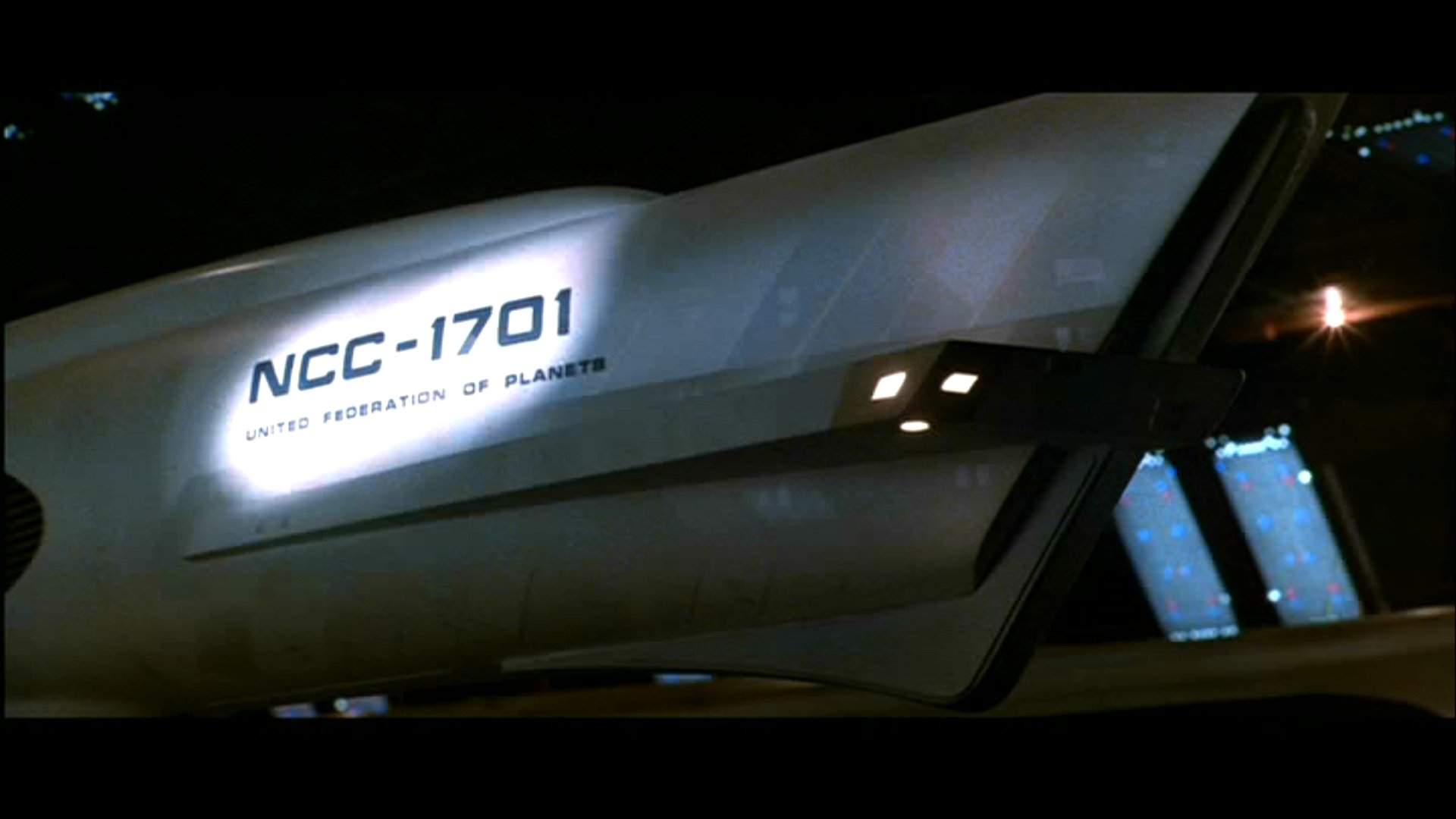 Close-up of the USS Enterprise NCC-1701 hull with lit windows against a dark space backdrop — movie: Star Trek II: The Wrath of Khan. HD PC desktop wallpaper / background.