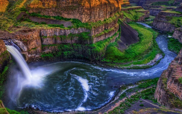 A stunning view of Palouse Falls cascading into a winding river, surrounded by moss-covered cliffs, showcasing the beauty of nature's vibrant landscape.