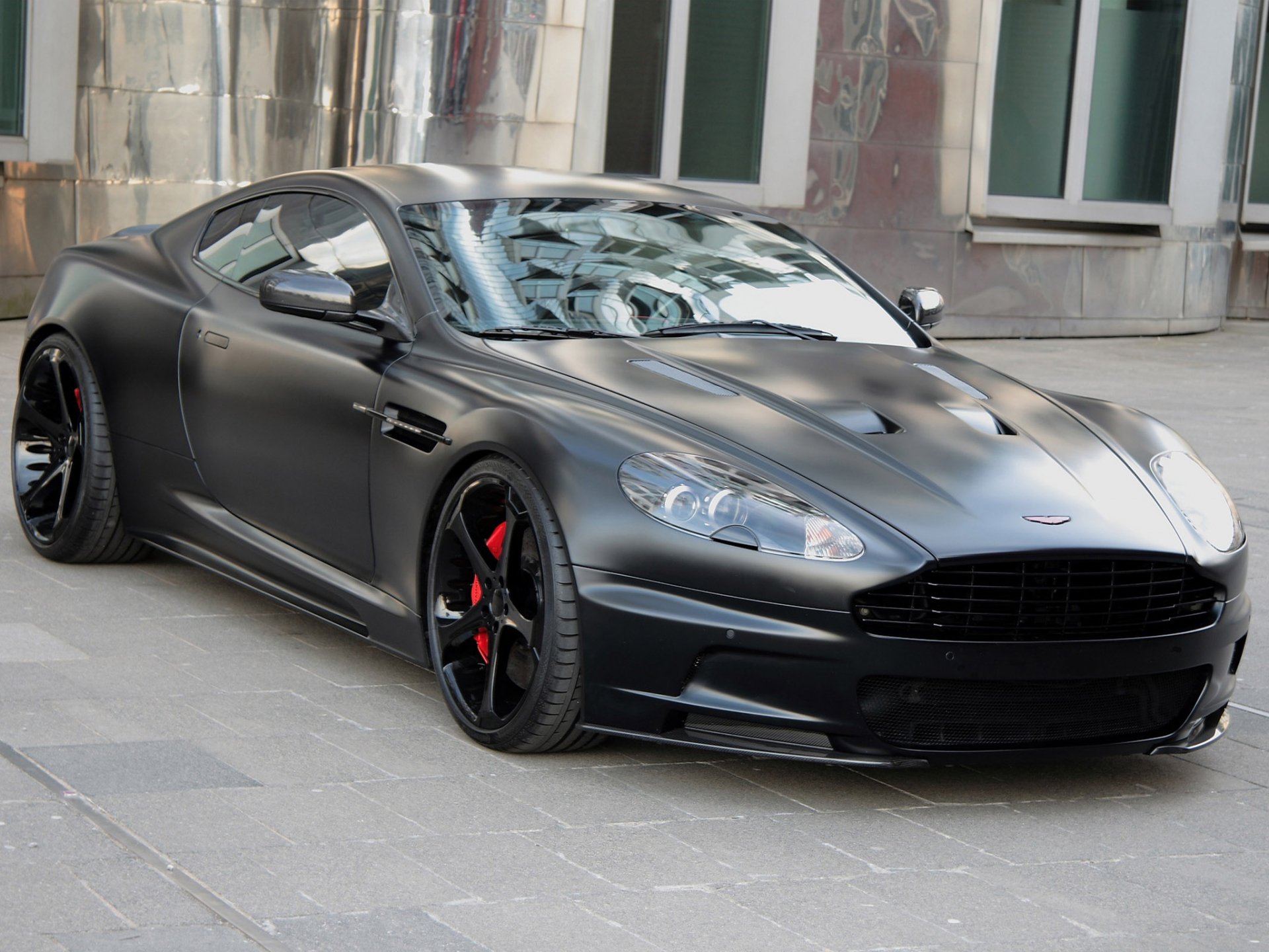 HD desktop wallpaper featuring a sleek black Aston Martin DBS parked on a city street, highlighting its aerodynamic design and sporty details.