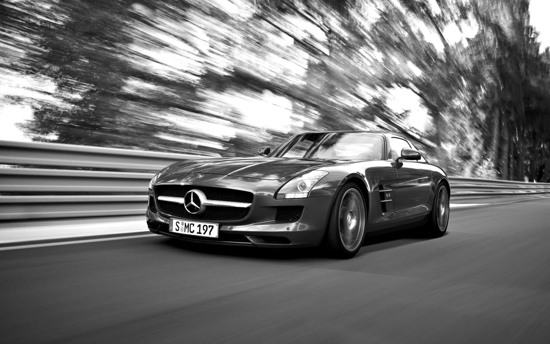 Black-and-white Mercedes sports car speeding past trees with motion blur; low-angle, high-contrast HD PC desktop wallpaper and background.