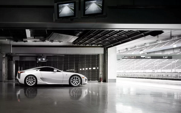 A sleek Lexus LFA Nurburgring Edition parked in a modern garage, showcasing its sporty design against a backdrop of empty racetrack and overhead monitors.