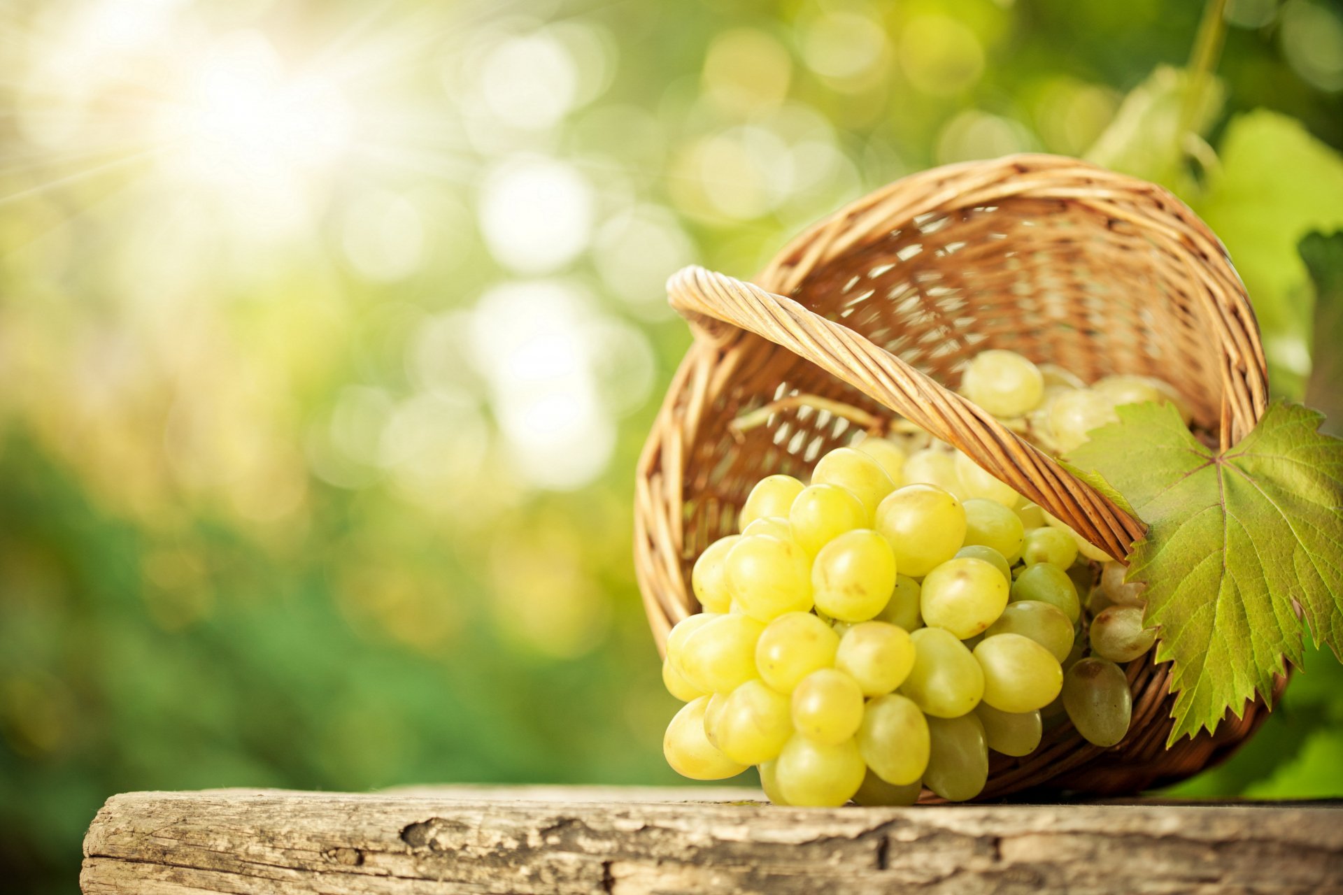 A cluster of green grapes spilling from a wicker basket on a wooden surface, captured in vibrant 4K Ultra HD quality with a softly blurred natural background.