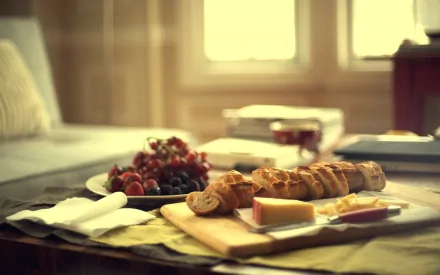 HD PC desktop wallpaper featuring a cozy meal setting with bread, cheese, and grapes on a table in warm natural light.