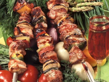 HD PC desktop wallpaper showing close-up of juicy barbecue skewers with grilled vegetables and a glass of iced tea, evoking a vibrant food and outdoor barbecue vibe.