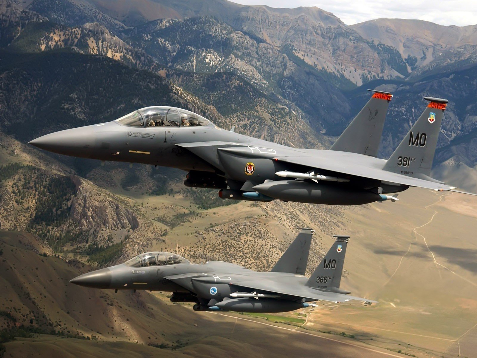 Military McDonnell Douglas F-15 Eagle fighters in flight over rugged mountains — HD PC desktop wallpaper and background.