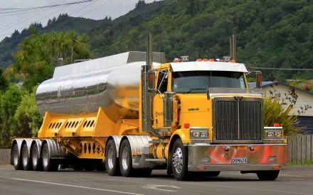 HD desktop wallpaper showing a yellow Western Star tanker truck parked on a road with green hills and palm trees in the background.