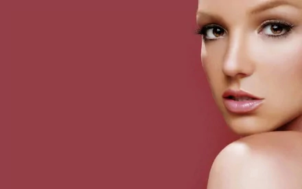 HD PC desktop wallpaper featuring a close-up portrait of Britney Spears against a solid muted red background, highlighting music and pop iconography.