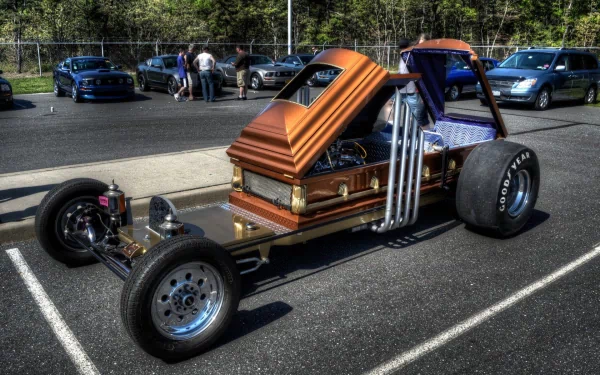 A creatively designed hot rod vehicle, featuring a coffin-inspired body, showcased in a parking lot with onlookers in the background. HD desktop wallpaper and background.